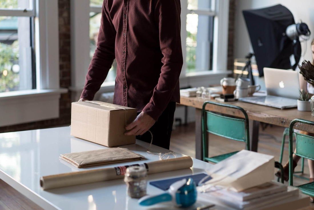 Person packing a cardboard box to ship a Shopify order.